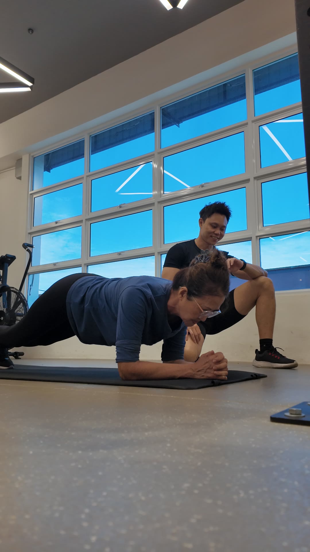 An older client holding a forearm plank with her coach at iLift Kuching
