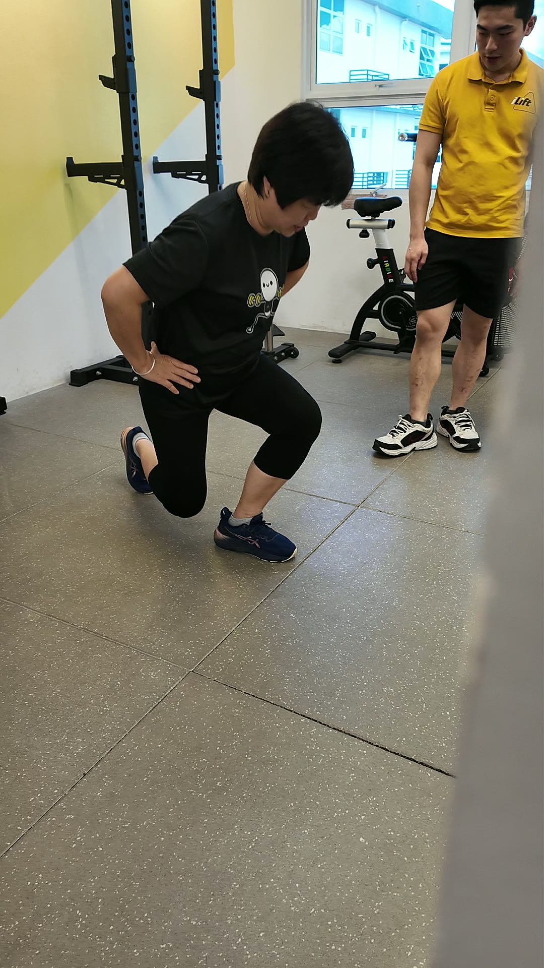 Mary doing a lunge while her coach watches her form at iLift Pines Square