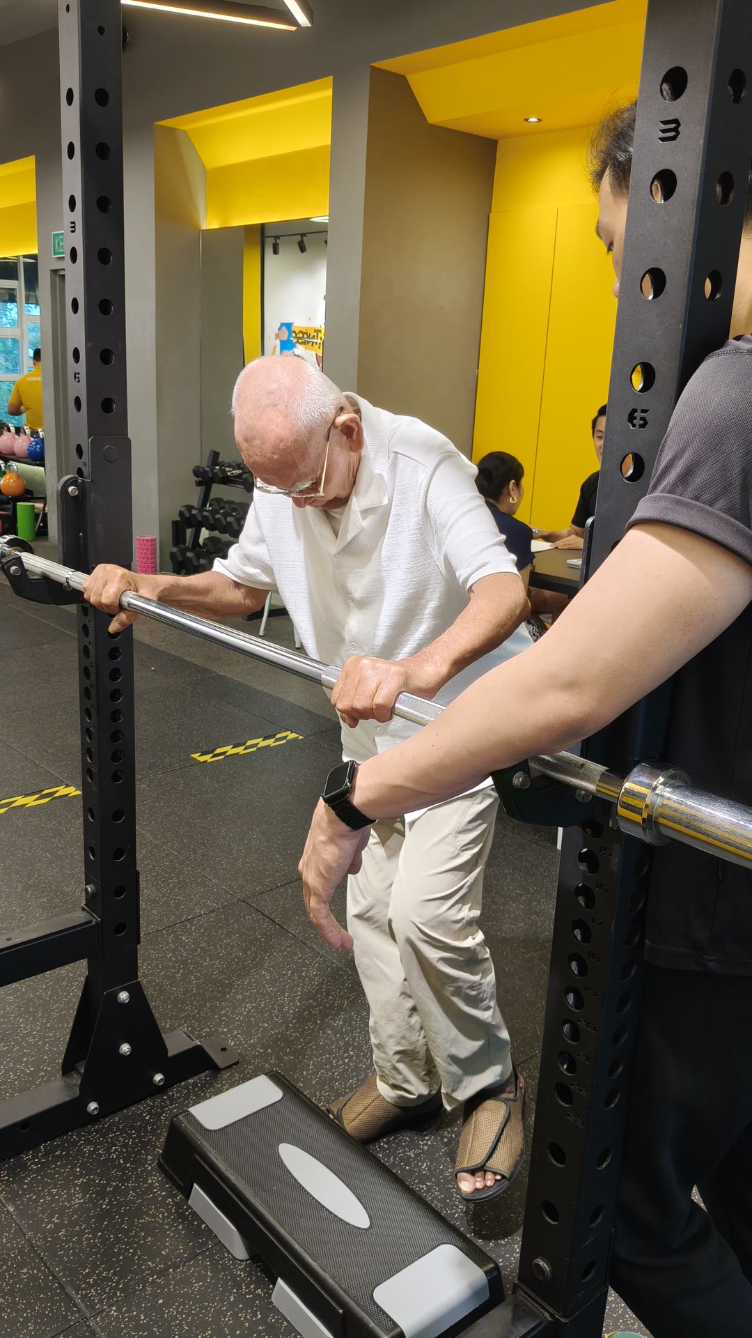 Wan doing a step-up while holding a bar for support at iLift